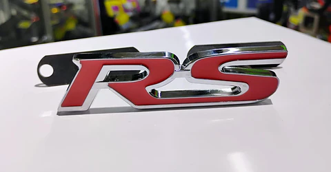 Emblema de parrilla apernado metalico modelo RS cromado con rojo
