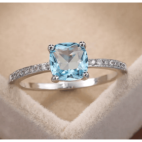 Anillo con topacio azul de imitación en corte cojín y circonias blancas redondas brazo media churumbela
