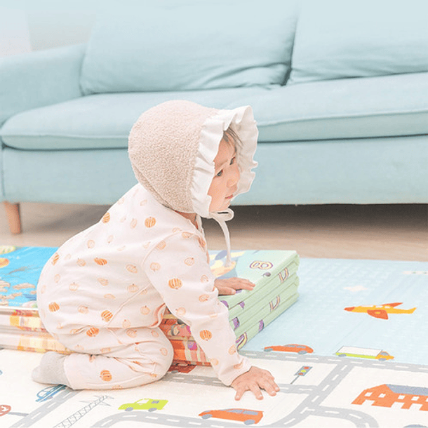 Bebé acostado sobre una colorida alfombra de juegos en el suelo en casa.