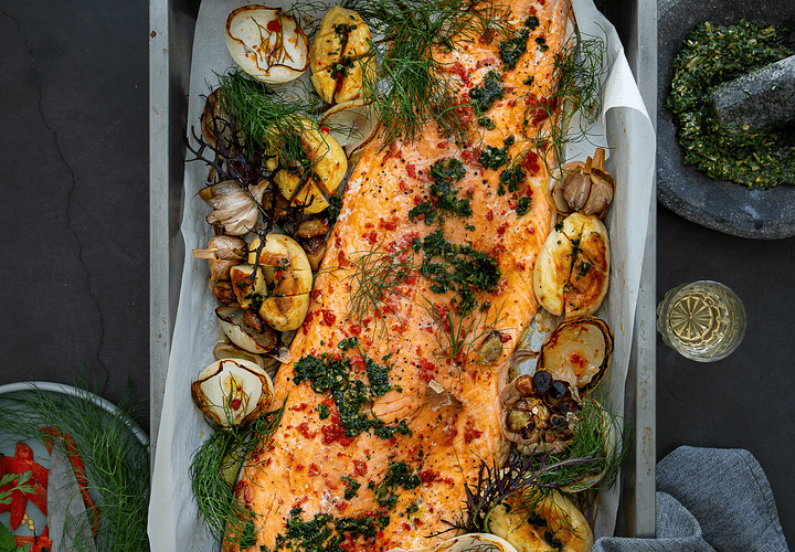 Filete de salmón al horno al pimentón, acompañado de papas asadas, ajo caramelizado, cebolla y pesto