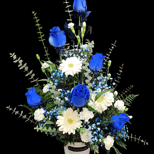 Vertical de rosas azules y gerberas en balde metálico.