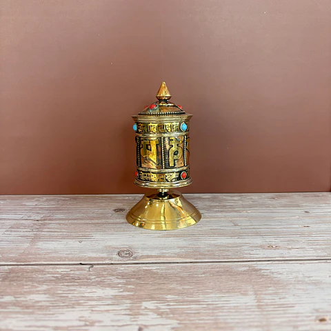 Rueda de rezo tibetana dorada con piedras