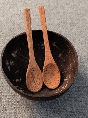 Una colección de cuatro artículos: dos cuencos de coco y dos cucharas de madera