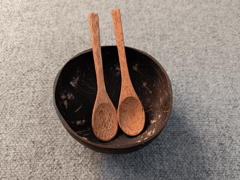 Una colección de cuatro artículos: dos cuencos de coco y dos cucharas de madera