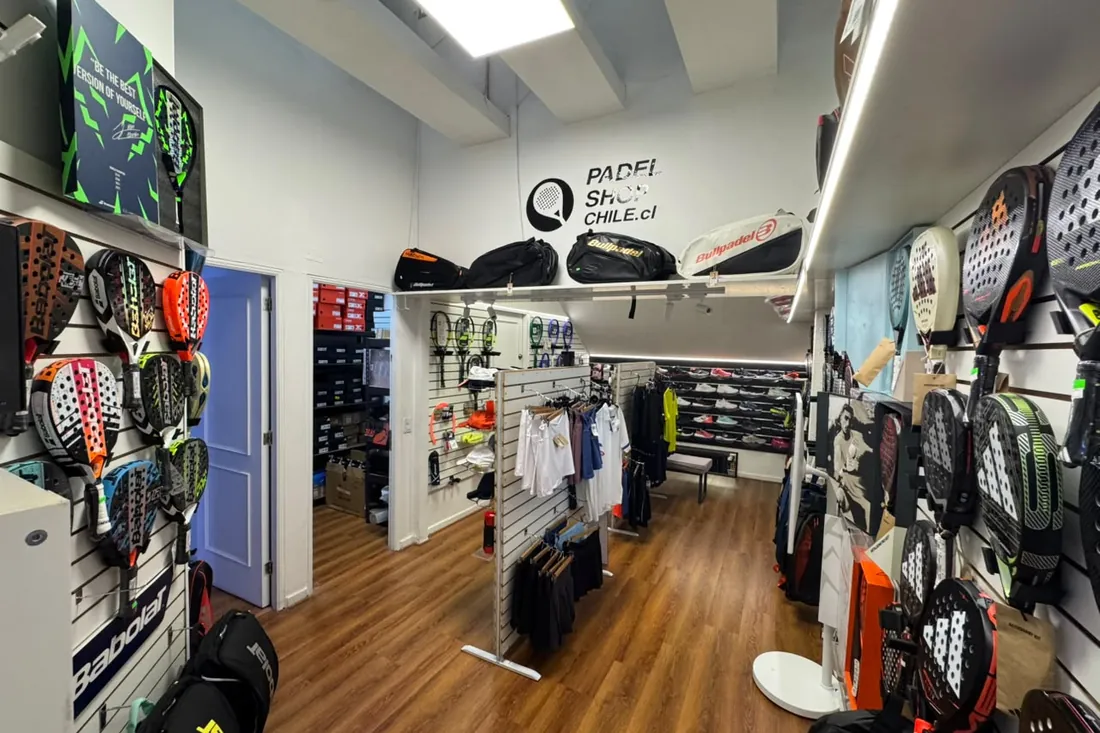 Interior de la tienda Padel Shop Chile en Los Cobres de Vitacura, con muro de palas de pádel y raquetas de tenis
