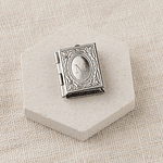 Relicario tipo libro con diseño plateado