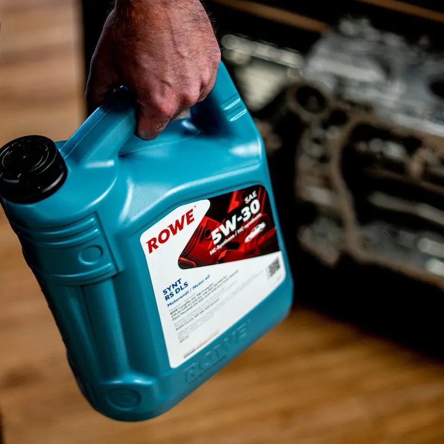 Bidón de aceite ROWE 5W-30 Synt RS DLS junto a un motor