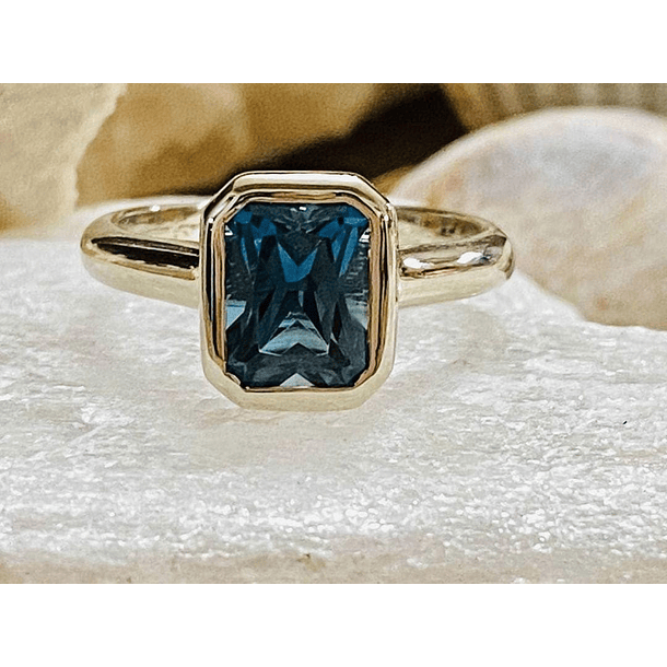 Anillo a bisel en oro amarillo de 14k con topacio london blue corte esmeralda talla 7.5 